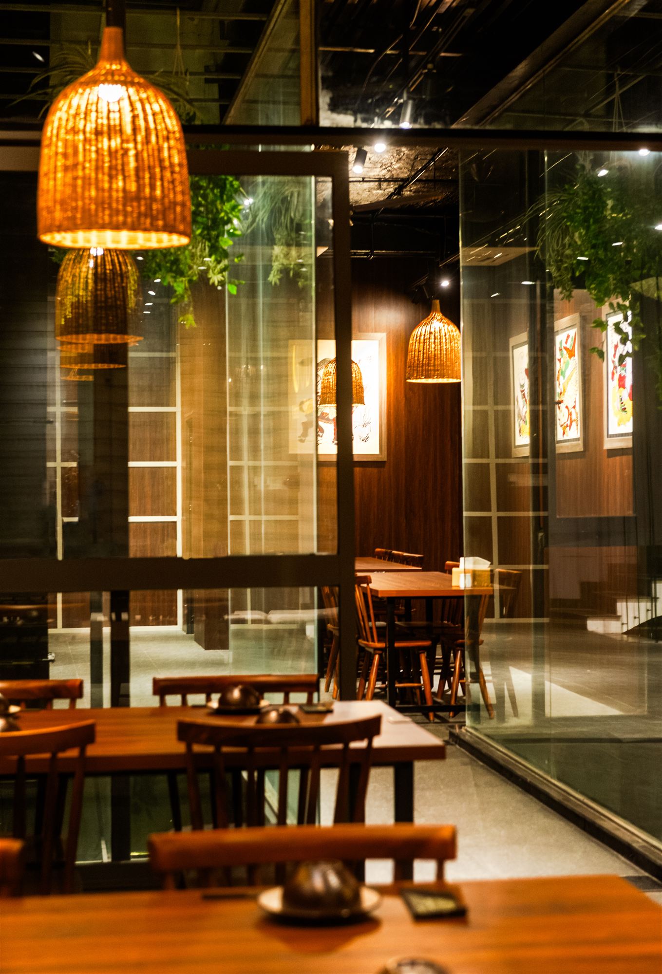 Glass corridor revealing the dining rooms beyond at night